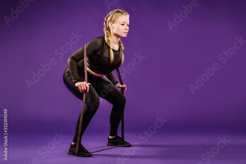 Young sportswoman doing exercises with rubber band