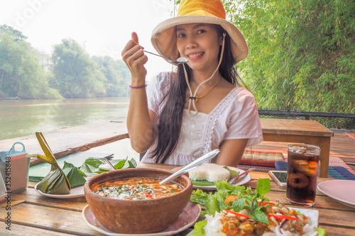 Woman wearing a yellow hat with Thai food on the waterfront atmosphere