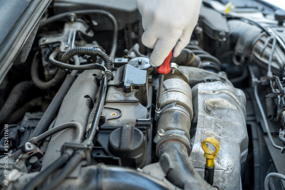 mechanic's hand with screwdriver repair or check car  in garage