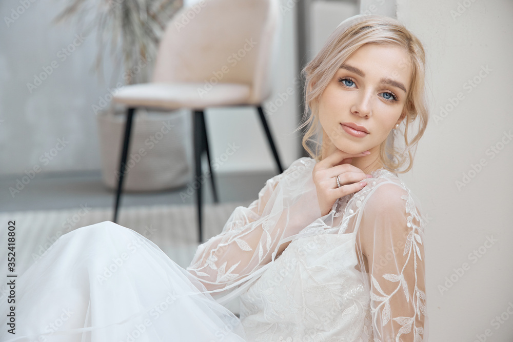 Ideal bride sitting on the floor, portrait of a girl in a long white dress. Beautiful hair and clean, soft skin. Wedding hairstyle blonde Ideal bride sitting on the floor, portrait of a girl in a long white dress. Beautiful hair and clean, soft skin. Wedding hairstyle blonde