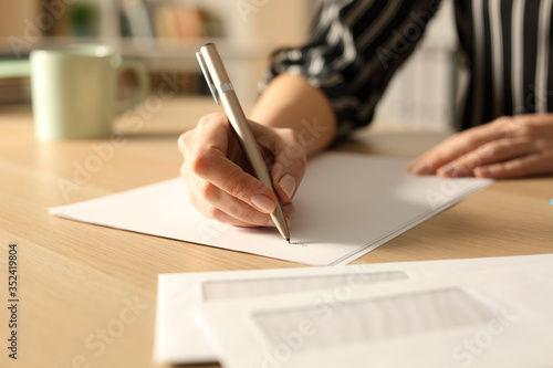 Woman hands writing letter in the night at home