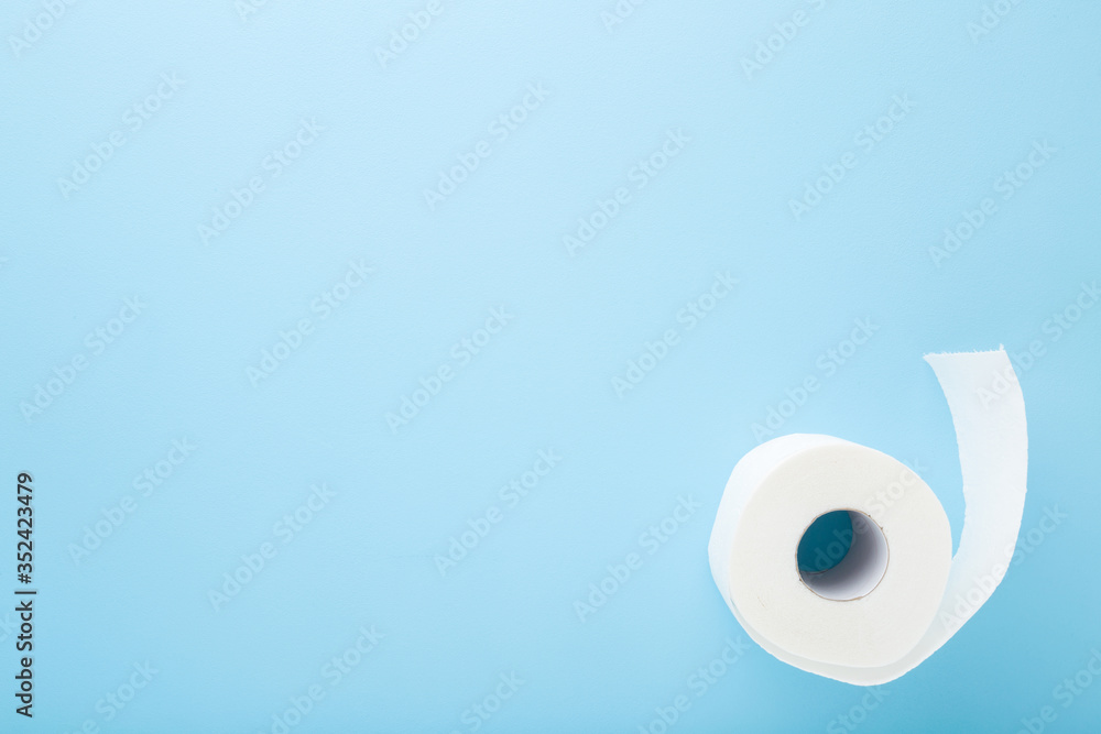 Soft, white toilet paper on light blue table background. Pastel color. Hygiene concept. Empty place for text or logo. Closeup. Top view.