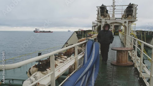 serious man with grey mustache walks confidently aboard industrial Natig Aliev tanker performing Skagen Danish port raid photo