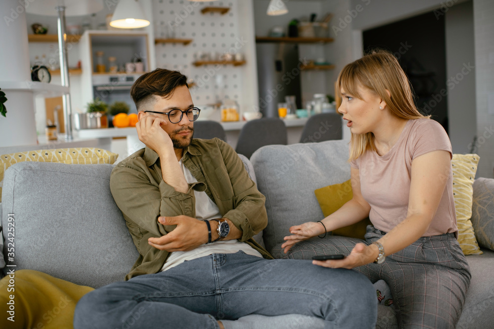 Husband and wife are arguing on the couch. Angry wife is yelling at her husband.. Husband and wife are arguing on the couch. Angry wife is yelling at her husband..
