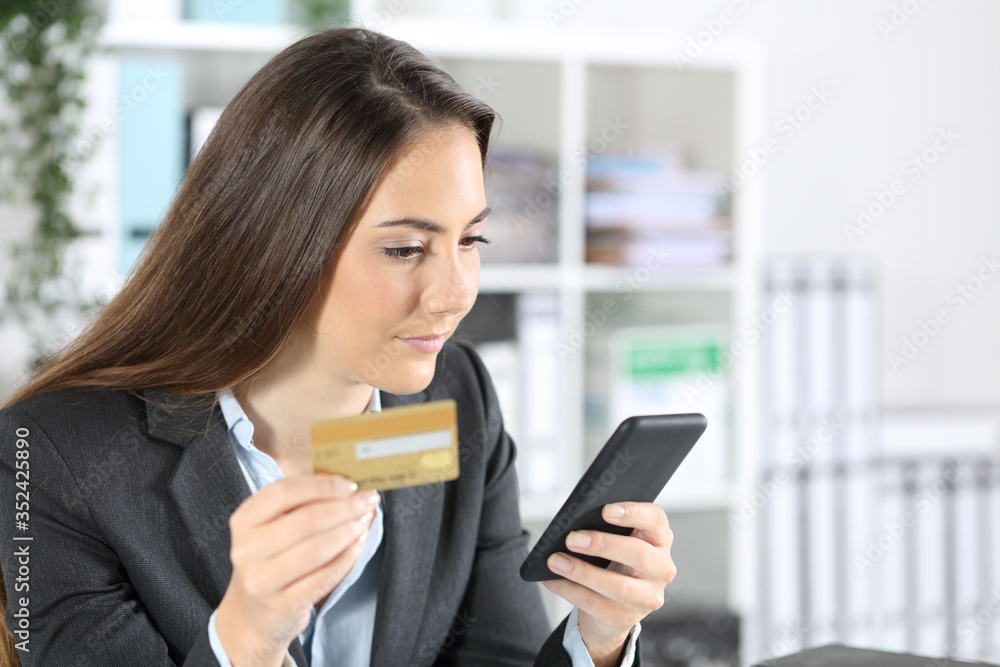 Executive woman paying on smart phone with card at office Executive woman paying on smart phone with card at office