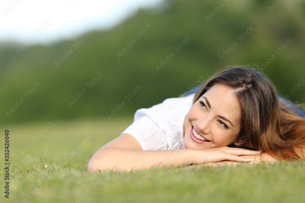 Happy woman lying on grass looking sideways on a park Happy woman lying on grass looking sideways on a park