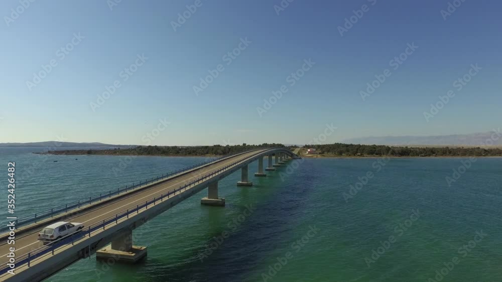 Aerial shot of vehicle on car over sea against blue sky, drone flying forward over ocean on sunny day - Razanac, Croatia Aerial shot of vehicle on car over sea against blue sky, drone flying forward over ocean on sunny day - Razanac, Croatia