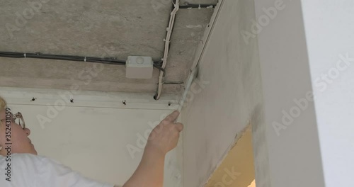 Elderly woman painter smears glue on walls, with brush thoroughly smears glue for wallpaper, makes repairs herself, no one helps, independent older generation, repair in apartment, wallpapering