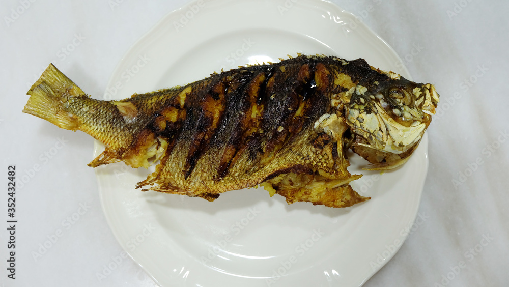 A whole fusilier fish, fried and served on a plate. Top view. A whole fusilier fish, fried and served on a plate. Top view.