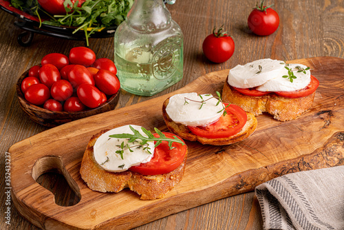 mozzarella with tomato slice on the toast on wooden board