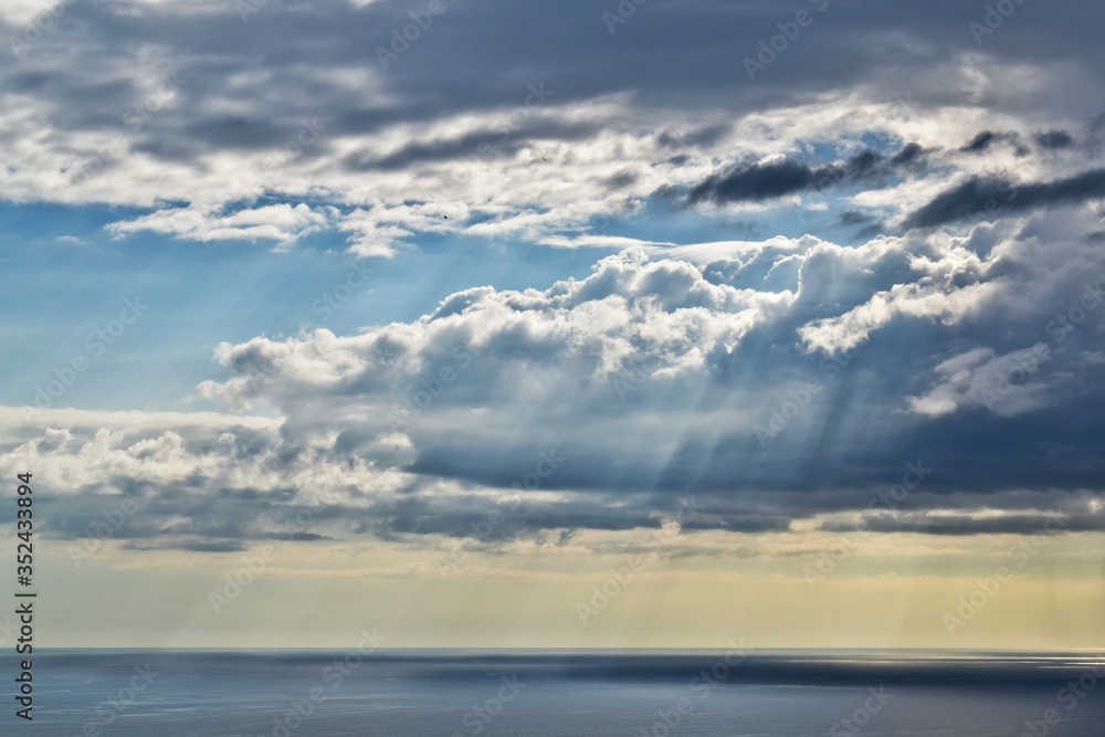 Sun rays and rain from a remote cloud at sea