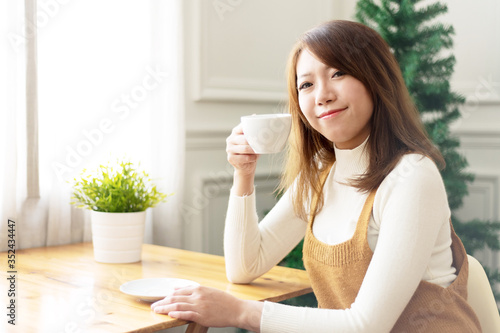 Young and pretty Asian girl with cup of coffee laughing in cafe