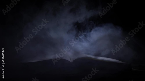 Old mystic book with open pages with magical smoke over black background.