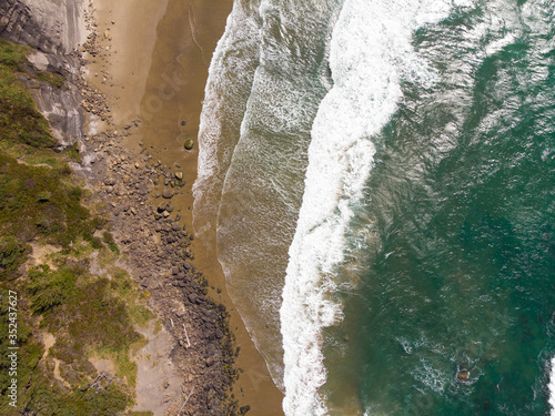 Pacific beach. Rocky beach and clear water waves. Top view, texture for design.