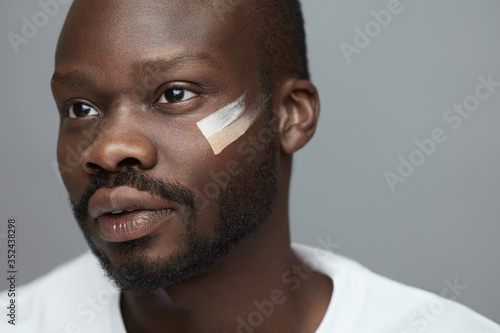 Male Makeup. Cosmetic Products On Facial Skin. African Model With Foundation Cream On Face. Beauty Routine Concept. photo