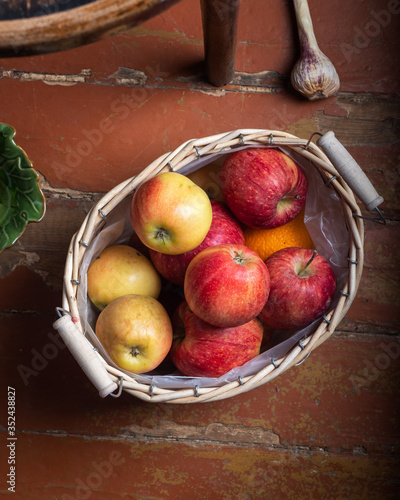 Basket with red and yellow apples standing on the floor
