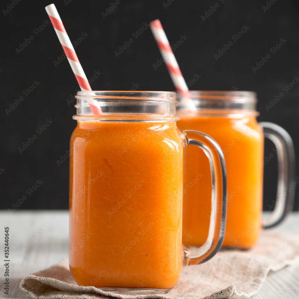 Homemade Mango Carrot Smoothie in glass jars, side view. Close-up. Homemade Mango Carrot Smoothie in glass jars, side view. Close-up.
