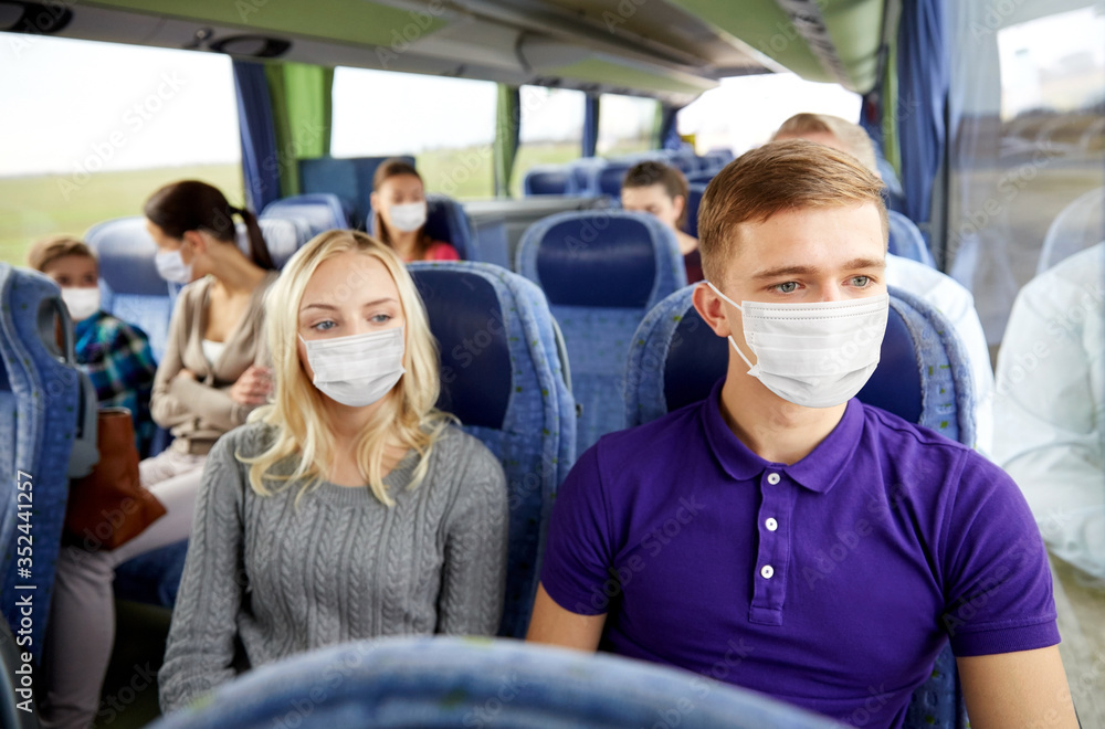 tourism, healthcare and pandemic concept - couple with group of passengers or tourists wearing face protective medical mask for protection from virus disease in travel bus - obrazy, fototapety, plakaty 