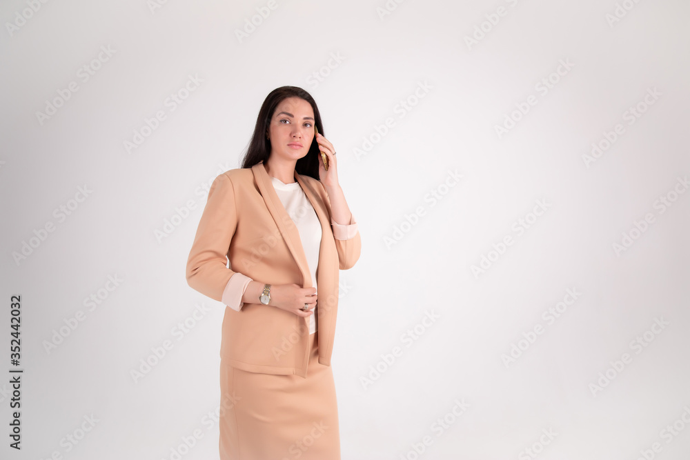 Successful business woman on grey background with copy space. chief in beige suit speaks by phone Successful business woman on grey background with copy space. chief in beige suit speaks by phone