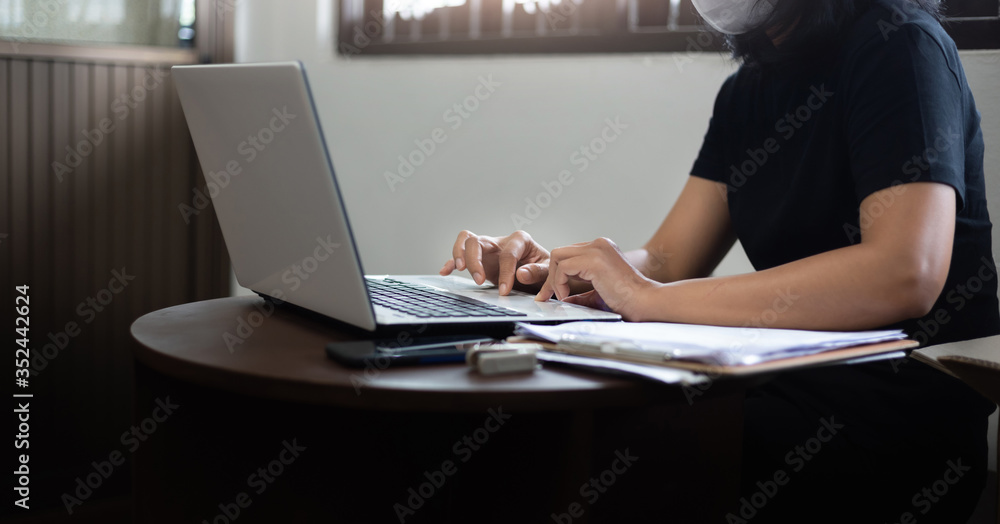 Fototapeta premium Young female wearing sanitation mask using laptop working online from home In a situation with an outbreak of coronavirus (covid-19), Concept work from home