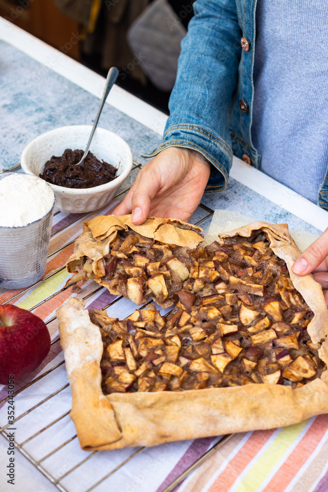 Apple crust tart pie with chocolate cream spread paste and cinnamon. Ingredients. Woman hands