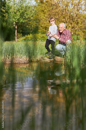 Großvater bringt Enkelsohn das Angeln bei am See