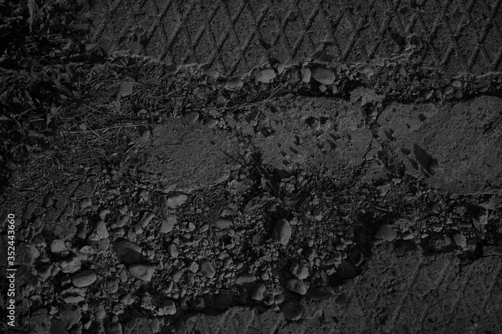Grunge gray background. Damaged sidewalk. Old broken sidewalk. Crushed stone concrete. Black and white stone background. Black grunge banner with crumbling concrete texture.