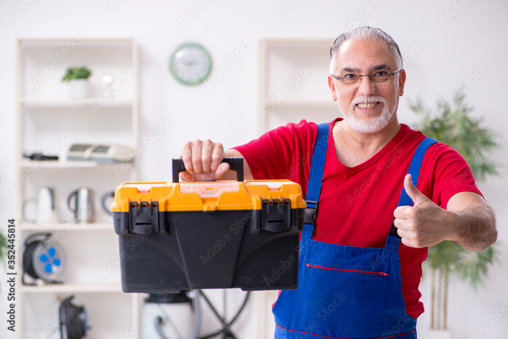 Old male contractor repairing household devices indoors Old male contractor repairing household devices indoors