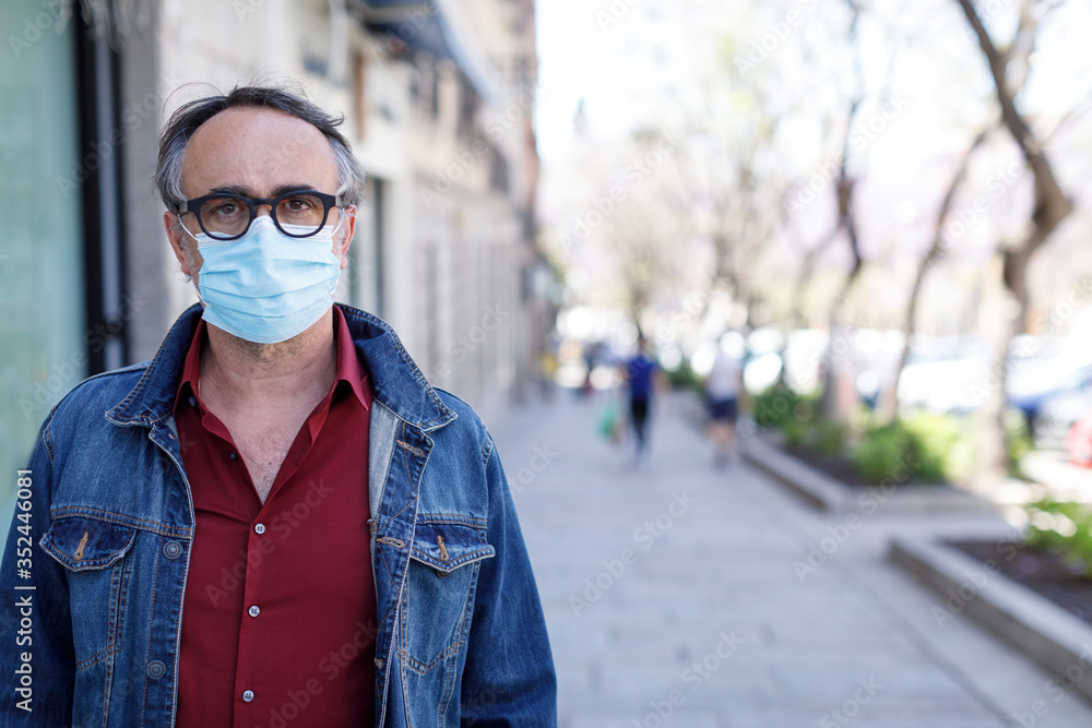 Uomo con mascherina vestito casual cammina per la città protetto dalla mascherina chirurgica Uomo con mascherina vestito casual cammina per la città protetto dalla mascherina chirurgica