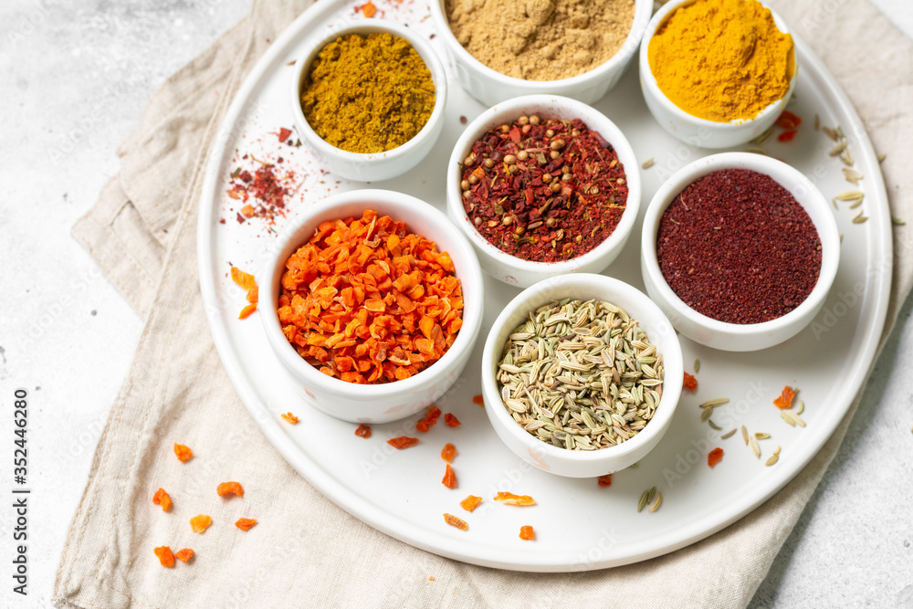 Spices and condiments in white bowls on a light gray table. Turmeric, ginger, curry, fennel and sumac in white bowls. Spices close up Spices and condiments in white bowls on a light gray table. Turmeric, ginger, curry, fennel and sumac in white bowls. Spices close up