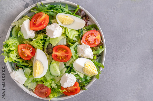 Eggs, tomatoes, cheese and lettuce on a plate. Vegetable salad. Top view, copy space