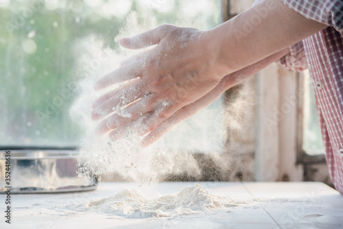 Woman is sifting a flour on the kitchen table close up.