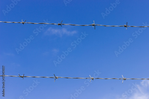 Two rows of barbed wire stretched against the sky