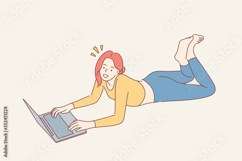 Home rest, leisure time concept. Young happy smiling woman girl teenager freelancer cartoon character lying on floor with laptop and looking straight at camera. Recreation and relaxation lifestyle.