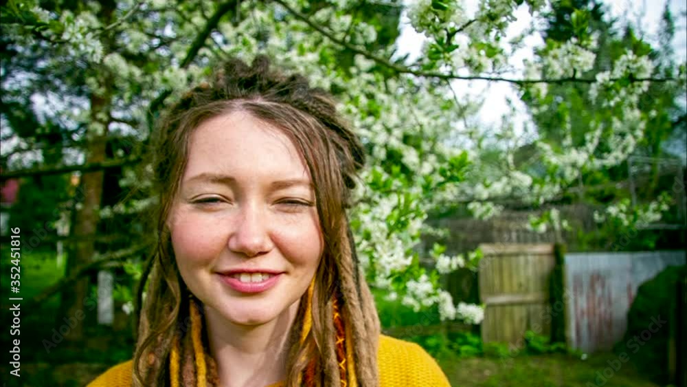 young woman with dreadlocks smiling in slow motion on a background of blooming cherry young woman with dreadlocks smiling in slow motion on a background of blooming cherry