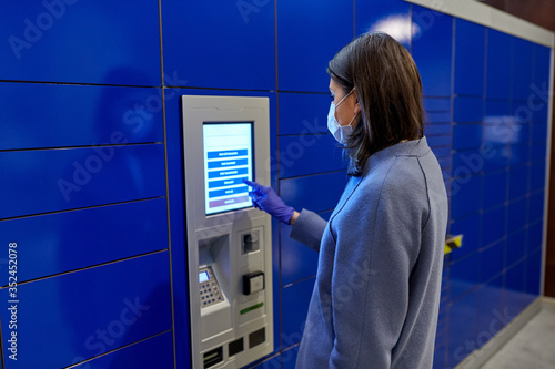 health care, mail delivery and pandemic concept - woman wearing face protective medical mask for protection from virus disease at automated parcel machine