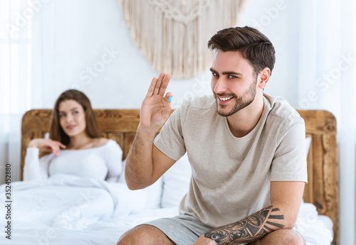Mens health and libido concept. Smiling man takes viagra before sex