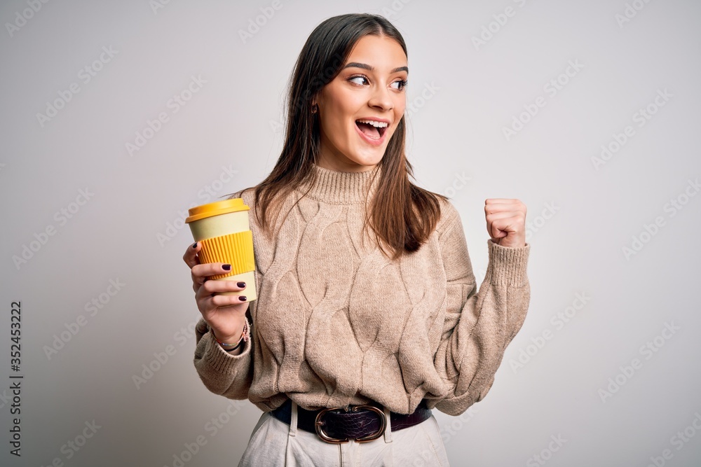 Young beautiful brunette woman drinking glass of coffee over isolated white background pointing and showing with thumb up to the side with happy face smiling Young beautiful brunette woman drinking glass of coffee over isolated white background pointing and showing with thumb up to the side with happy face smiling