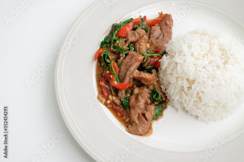 Spicy stir-fried pork basil in a white plate on white table, Traditional thai food