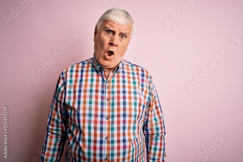 Senior handsome hoary man wearing casual colorful shirt over isolated pink background In shock face, looking skeptical and sarcastic, surprised with open mouth © Krakenimages.com