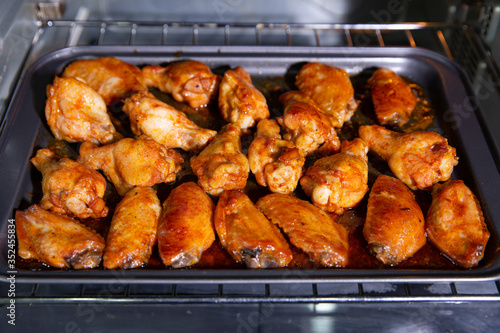 Chicken wings baked on a stainless steel tray in the microwave.