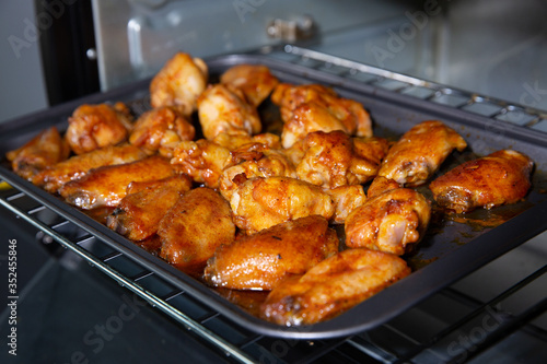 Chicken wings baked on a stainless steel tray in the microwave.
