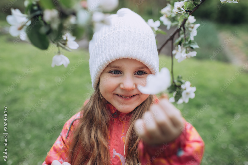 Little girl touching blooming tree and smiling Little girl touching blooming tree and smiling