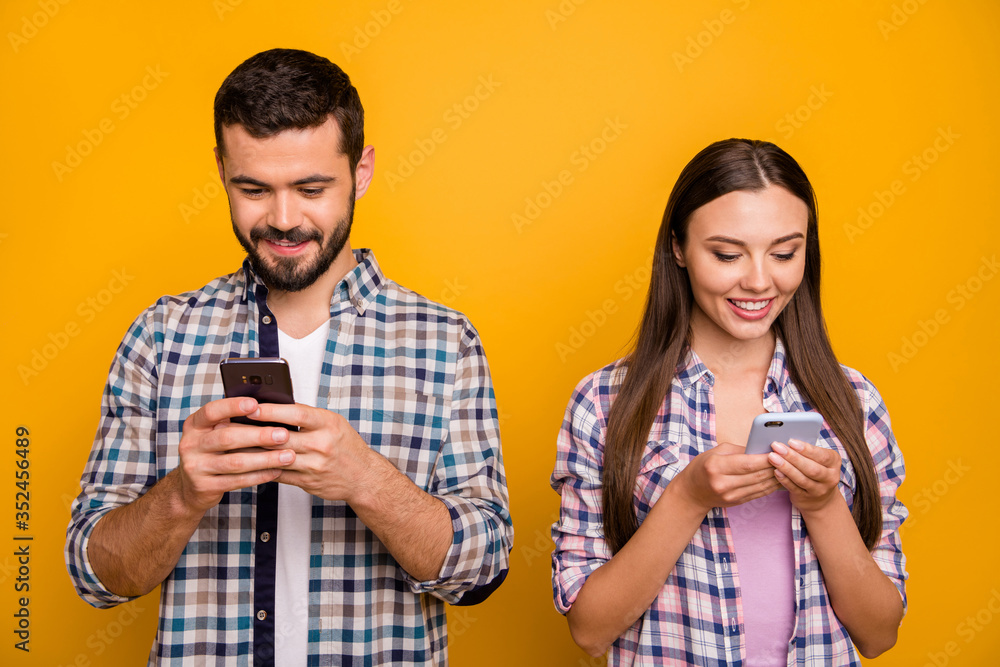 Photo attractive lady handsome cheerful guy couple look telephone screen addicted users popular bloggers wear casual plaid shirts outfit isolated yellow color background Photo attractive lady handsome cheerful guy couple look telephone screen addicted users popular bloggers wear casual plaid shirts outfit isolated yellow color background