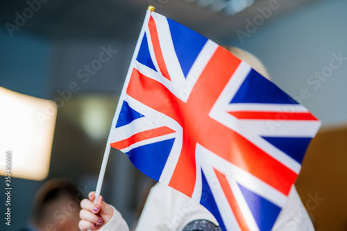 Kid's hands are holding England UK Flag. Studing foreign languages. English lesson. Closeup.