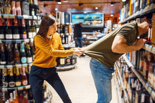 Funny couple choosing alcohol in grocery store