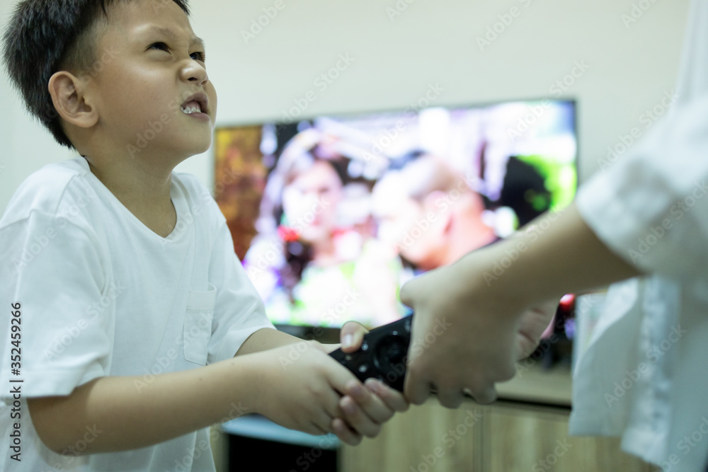 Sister, little brother fighting to get the remote control,asian sibling,aggressive kid boy and child girl fighting over the TV remote control,addicted to cartoons on television while stay at home