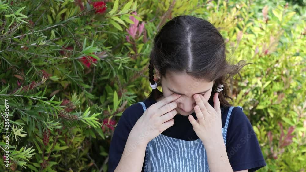 Allergy sick girl rubbing her itchy eyes in the park Allergy sick girl rubbing her itchy eyes in the park