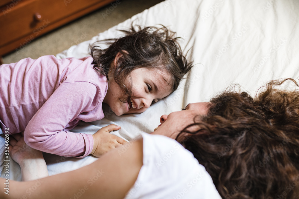 Little girl and mother laughing while lying in bed Little girl and mother laughing while lying in bed