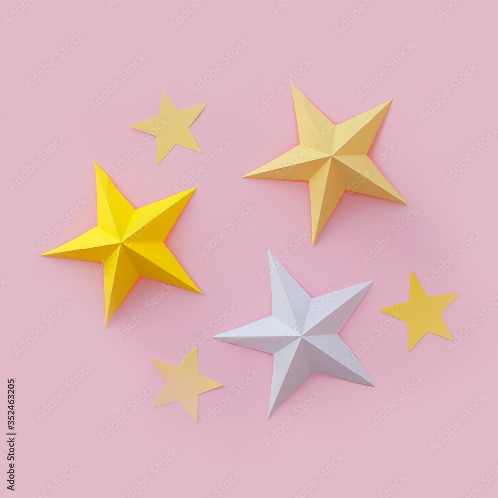 Handmade paper art and cut white and yellow stars on pink background. 